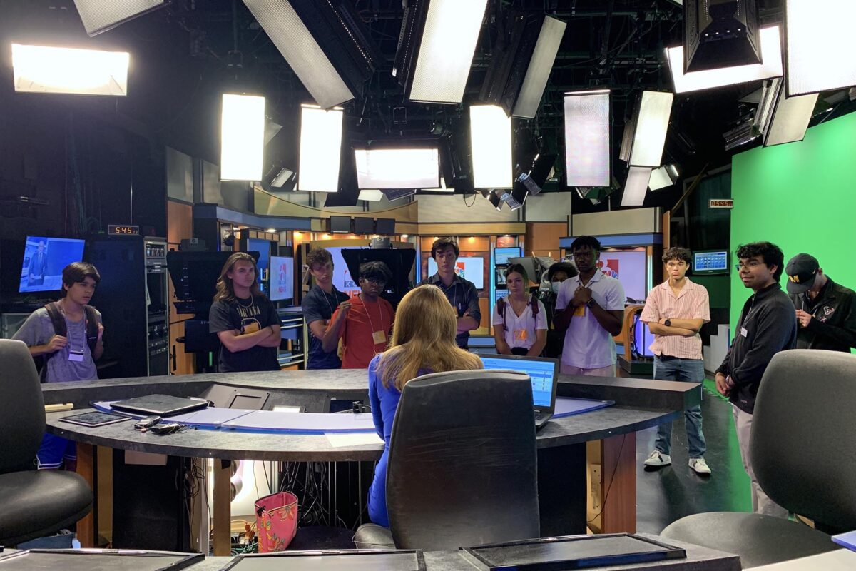 Students listen to an anchor speak inside KOMU's news studio.